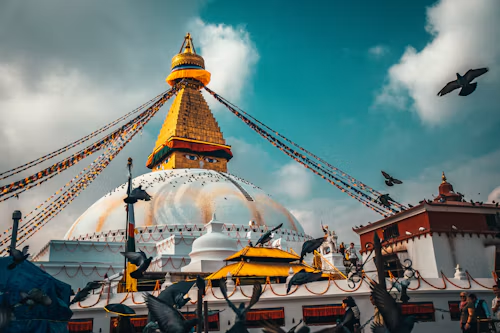 Boudhanath Stupa in Kathmandu with prayer flags and birds in the sky
