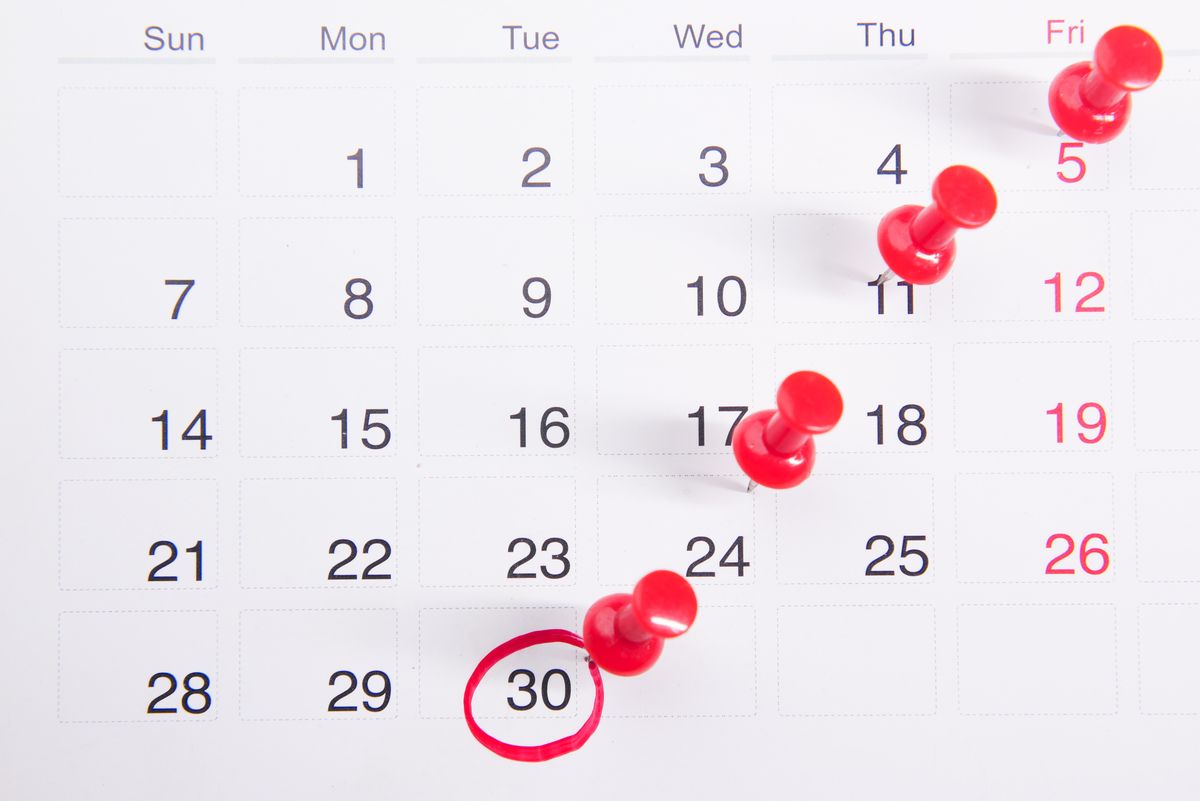 Close-up of a calendar page marked with red pins